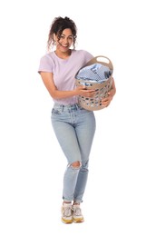 Happy woman with basket full of laundry on white background