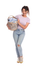 Happy woman with basket full of laundry on white background