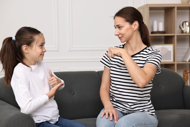 Photo of Woman and her daughter using sign language for communication at home