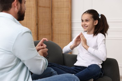 Photo of Man and his daughter using sign language for communication at home