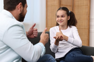 Photo of Man and his daughter using sign language for communication at home