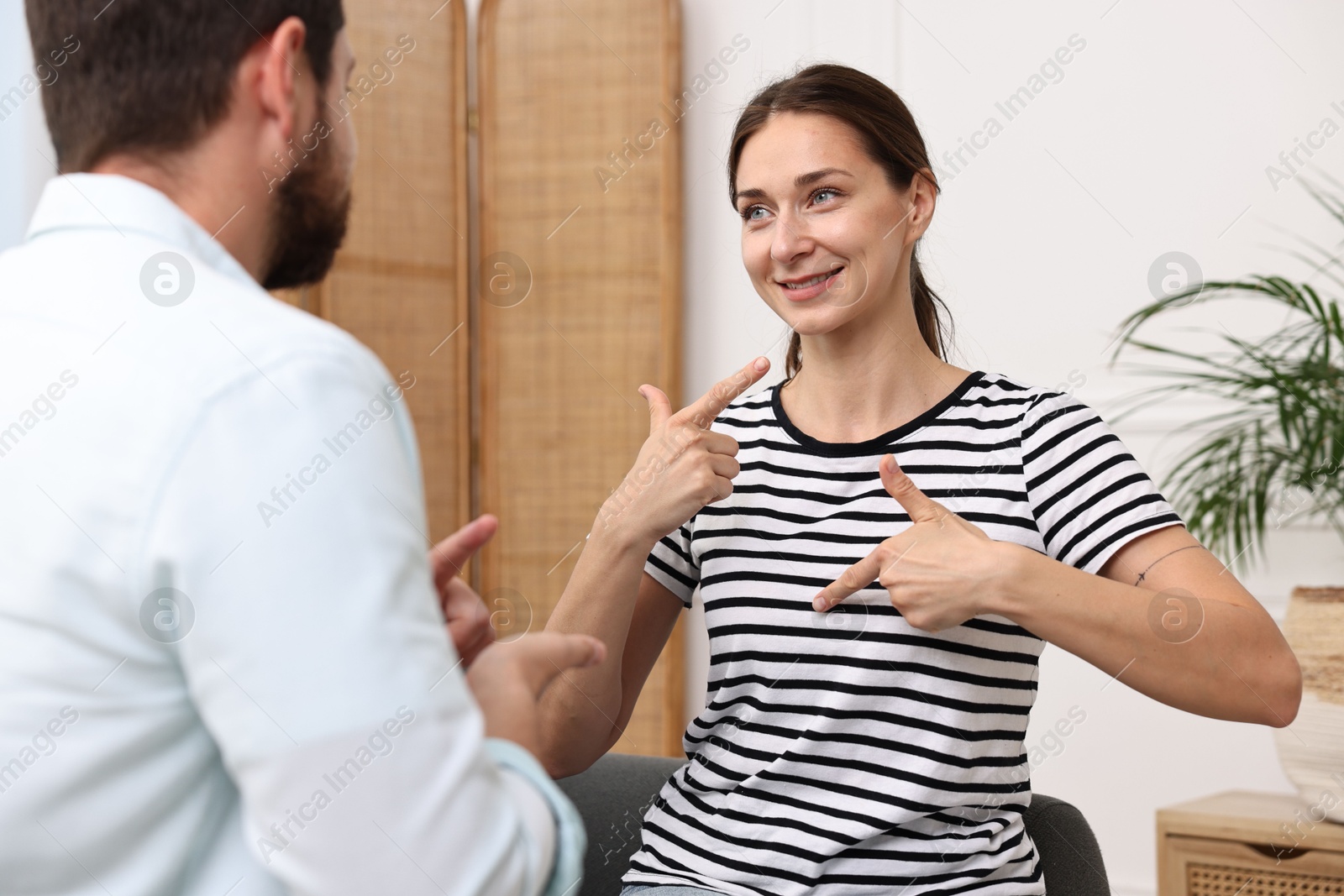 Photo of Man and woman using sign language for communication at home