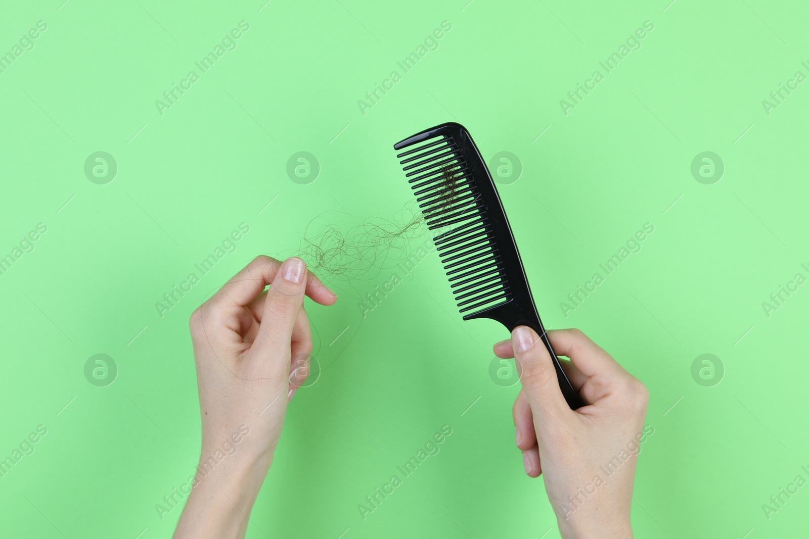 Photo of Woman taking lost hair from brush on green background, top view