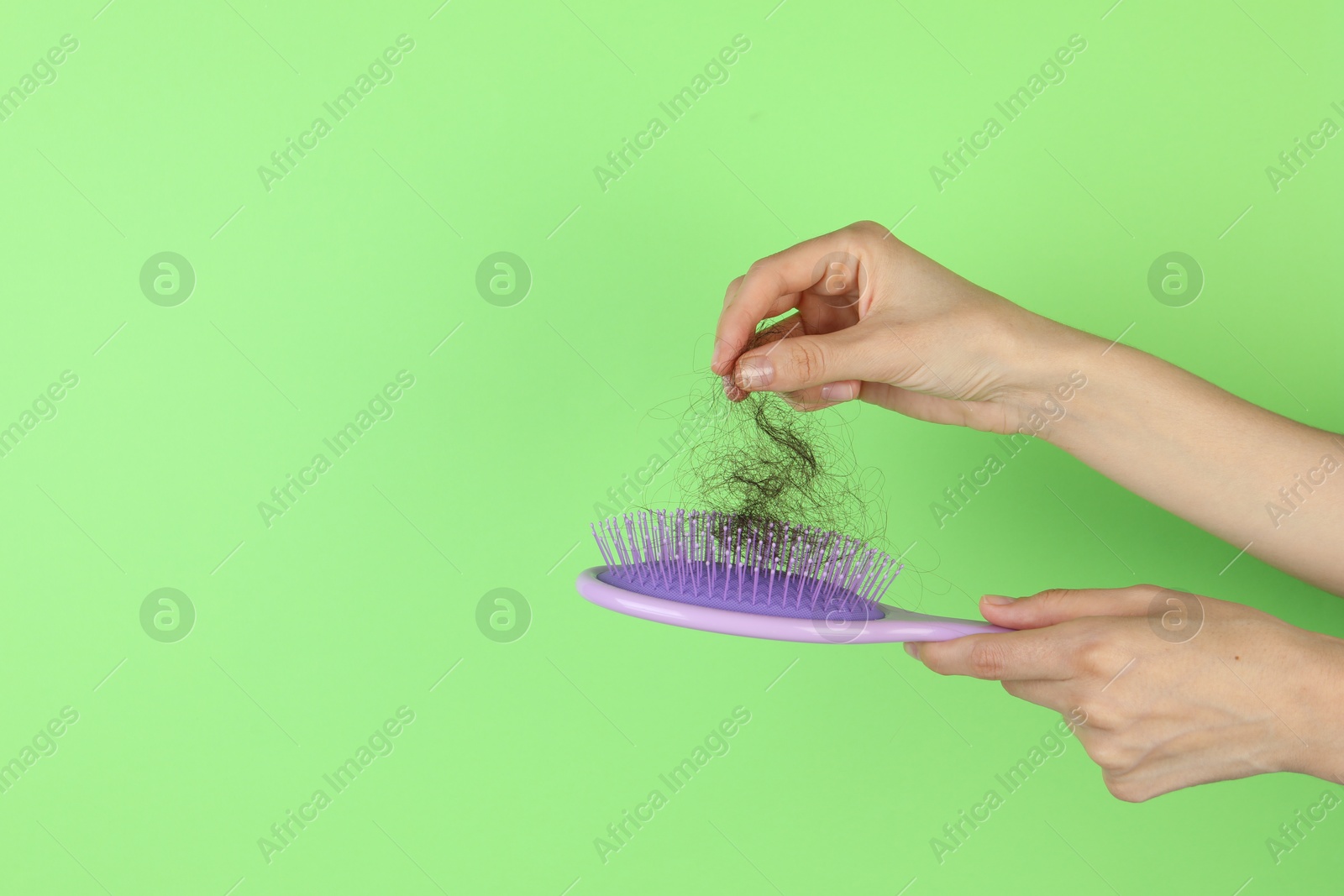 Photo of Woman taking lost hair from brush on green background, closeup. Space for text