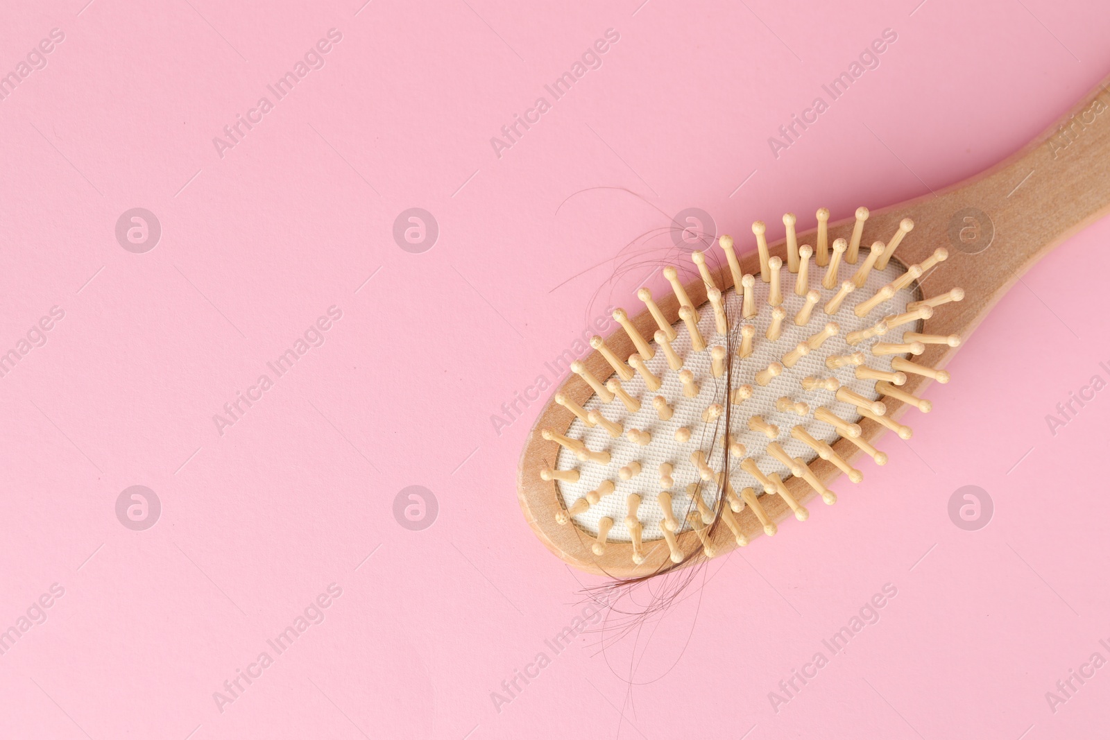 Photo of One brush with lost hair on pink background, top view. Space for text