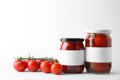 Tasty pickled tomatoes in jars and vegetables on light background. Space for text