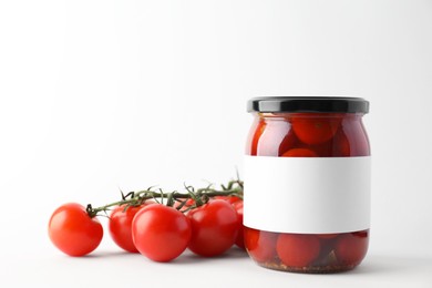 Tasty pickled tomatoes in jar and vegetables on light background