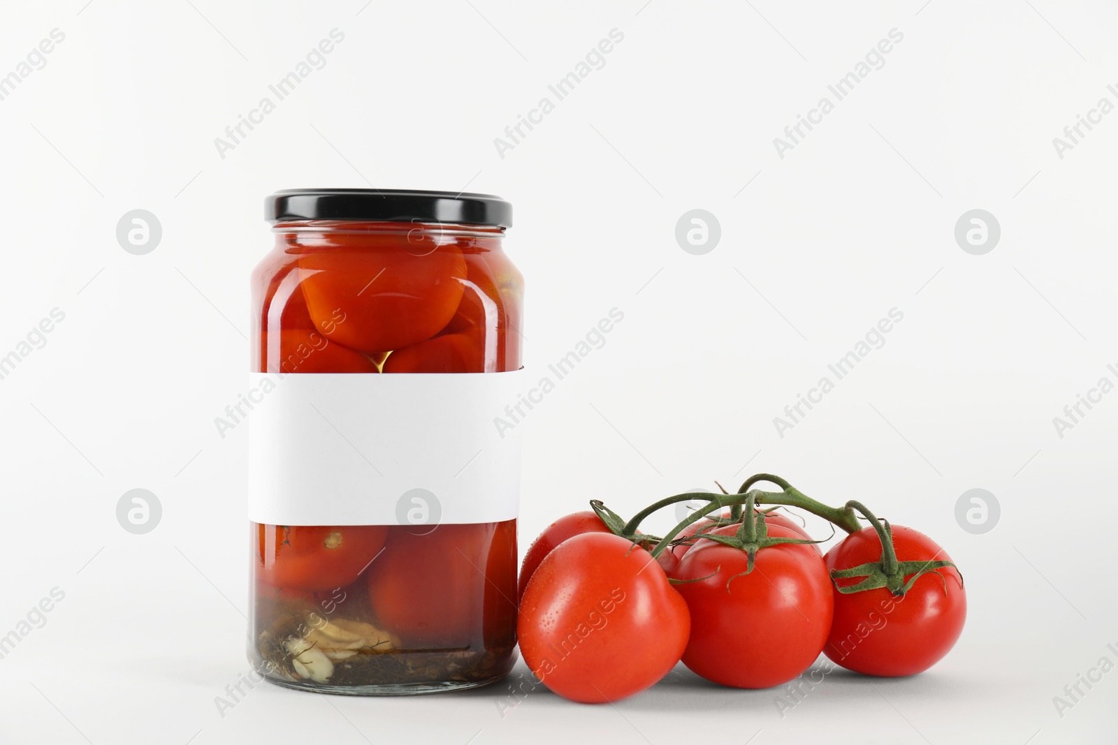 Photo of Tasty pickled tomatoes in jar and vegetables on light background