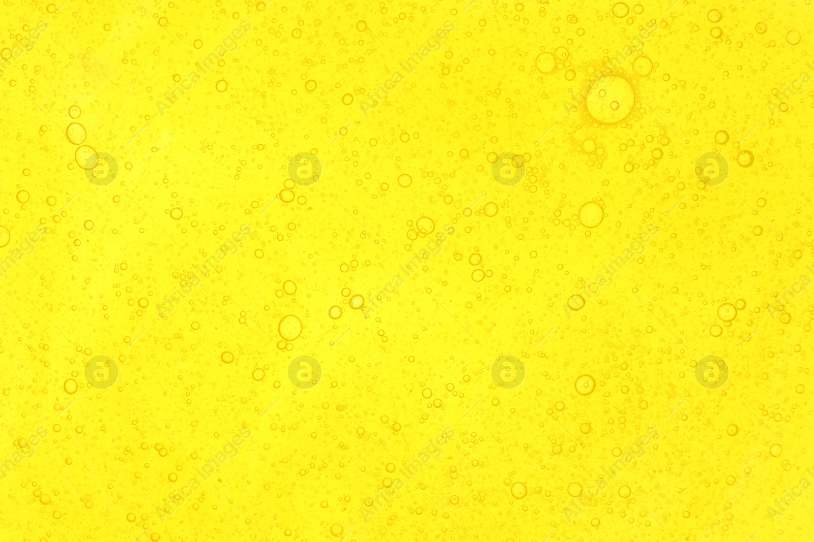 Photo of Bright yellow liquid as background, top view