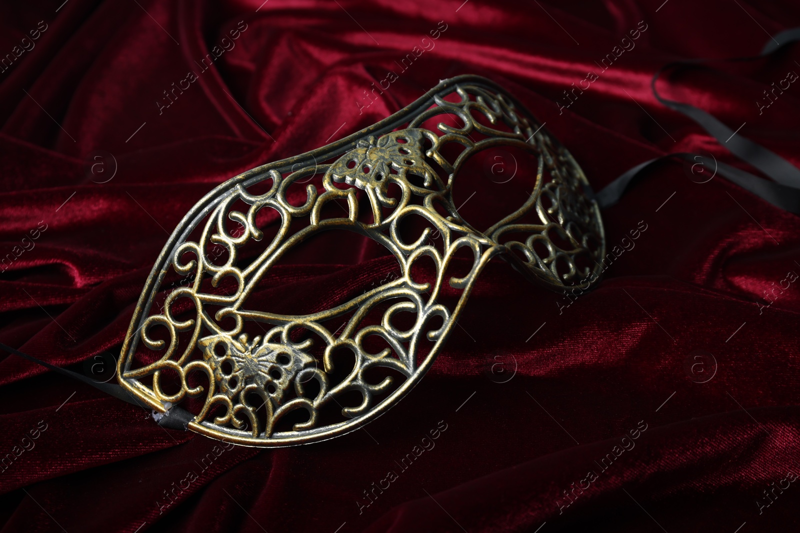 Photo of One beautiful carnival mask on red fabric, closeup