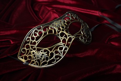 Photo of One beautiful carnival mask on red fabric, closeup