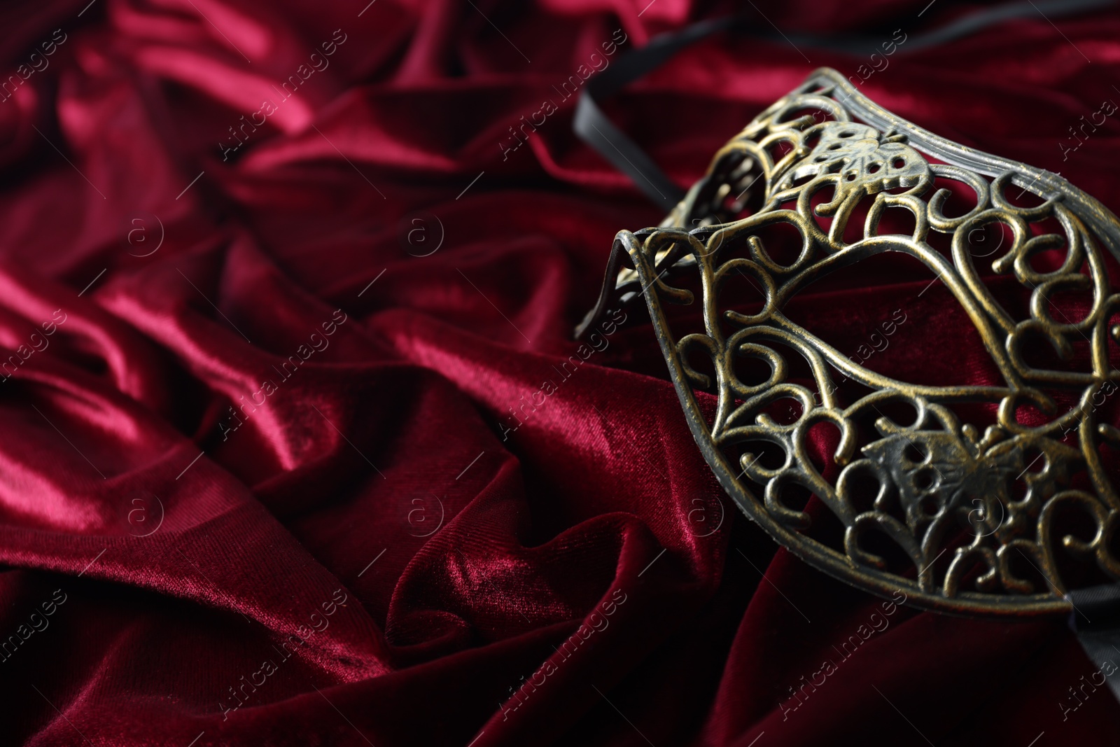 Photo of One beautiful carnival mask on red fabric, space for text