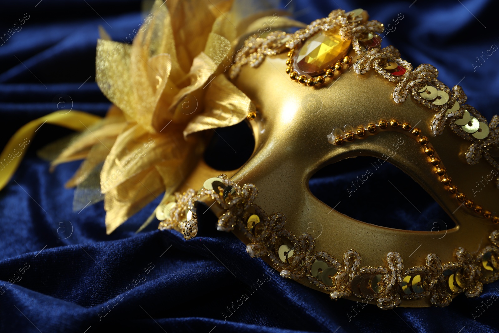 Photo of One beautiful carnival mask on blue fabric, closeup