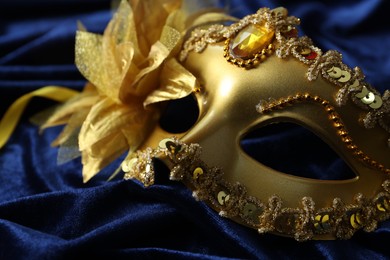 Photo of One beautiful carnival mask on blue fabric, closeup