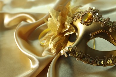 One beautiful carnival mask on golden fabric, closeup. Space for text