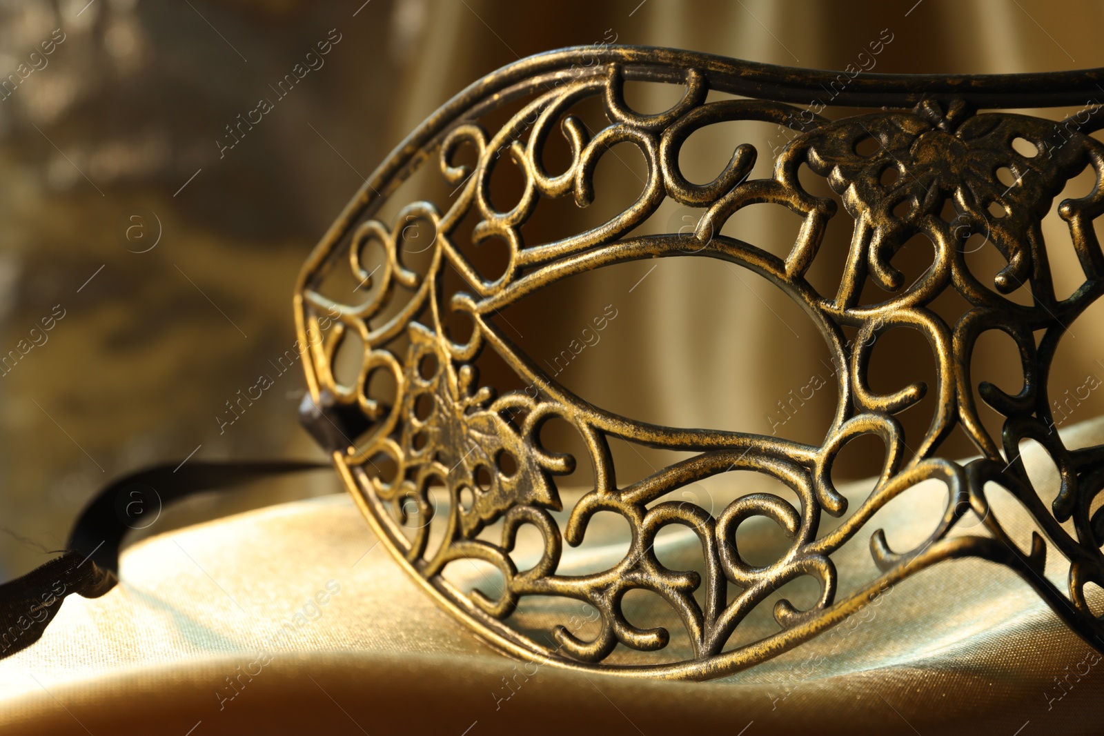 Photo of One beautiful carnival mask on golden fabric, closeup