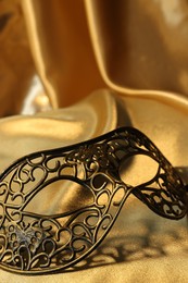 Photo of One beautiful carnival mask on golden fabric, closeup