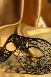 Photo of One beautiful carnival mask on golden fabric, closeup