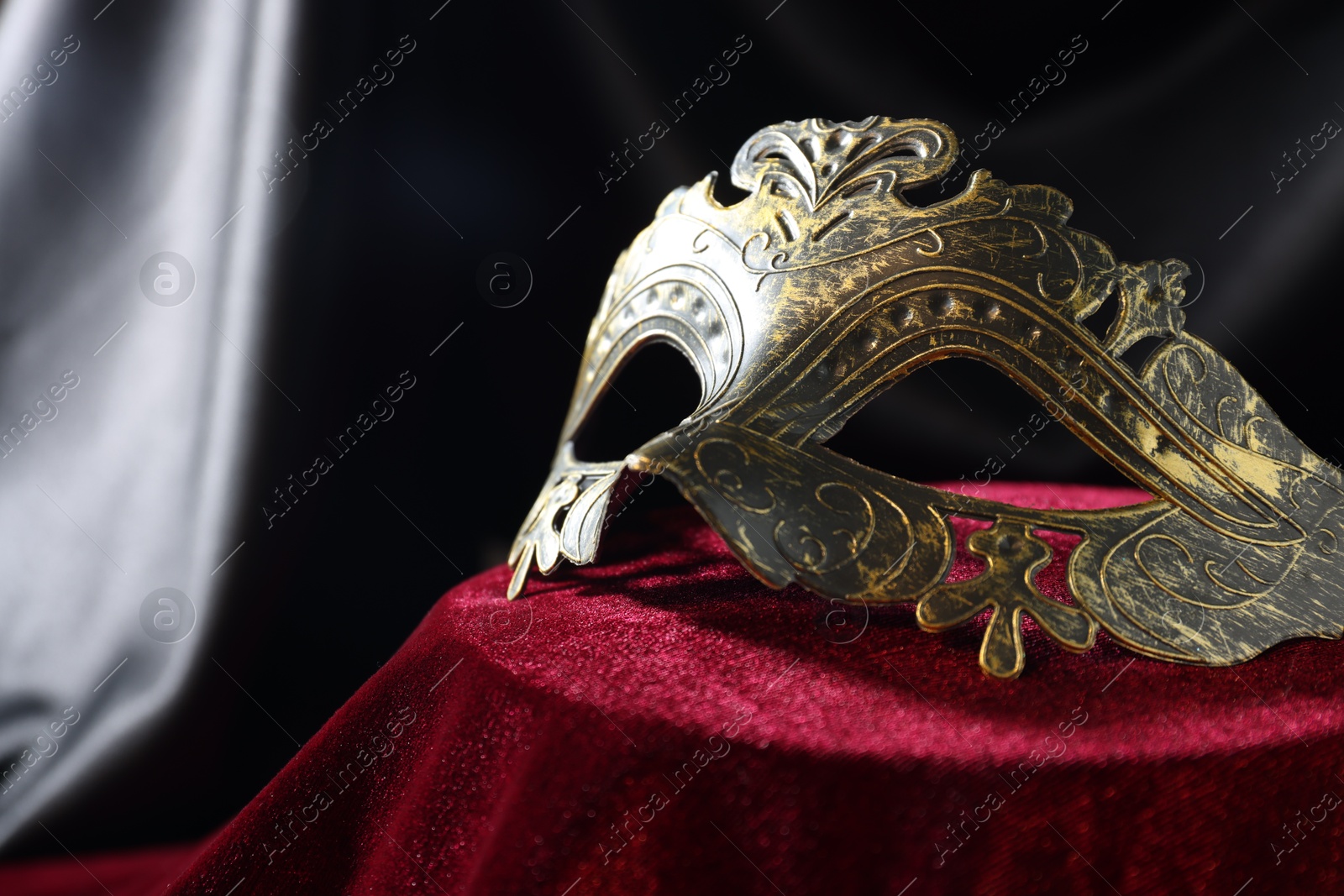 Photo of One beautiful carnival mask on red fabric, closeup