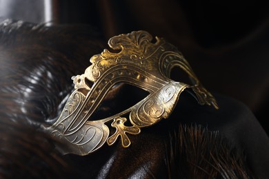 Photo of Beautiful carnival mask and feathers on black fabric, closeup