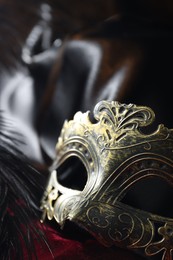 Beautiful carnival mask and feather on red fabric, closeup