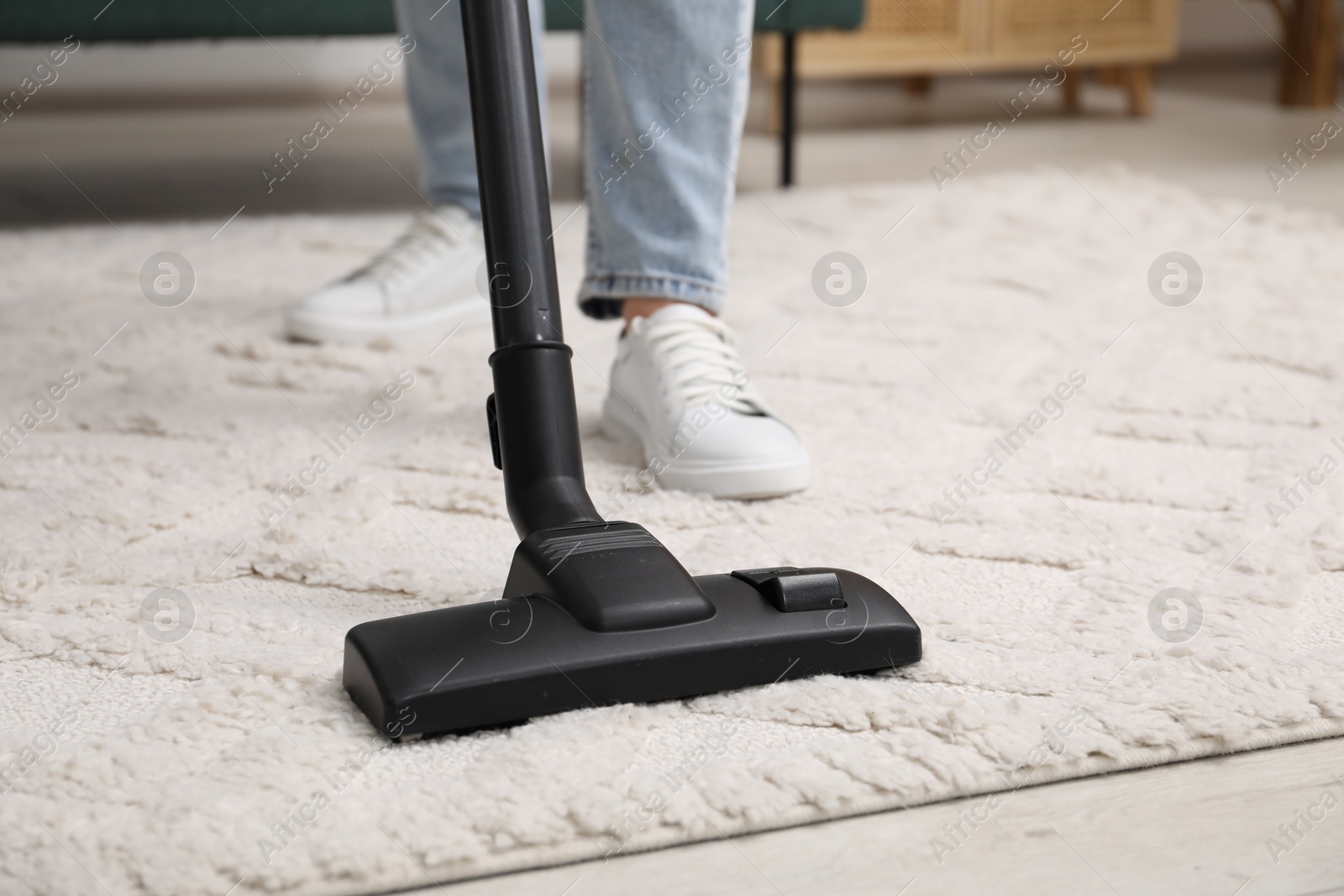 Photo of Woman cleaning carpet with vacuum indoors, closeup