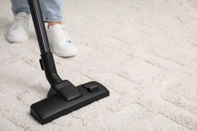 Photo of Woman cleaning carpet with vacuum indoors, closeup