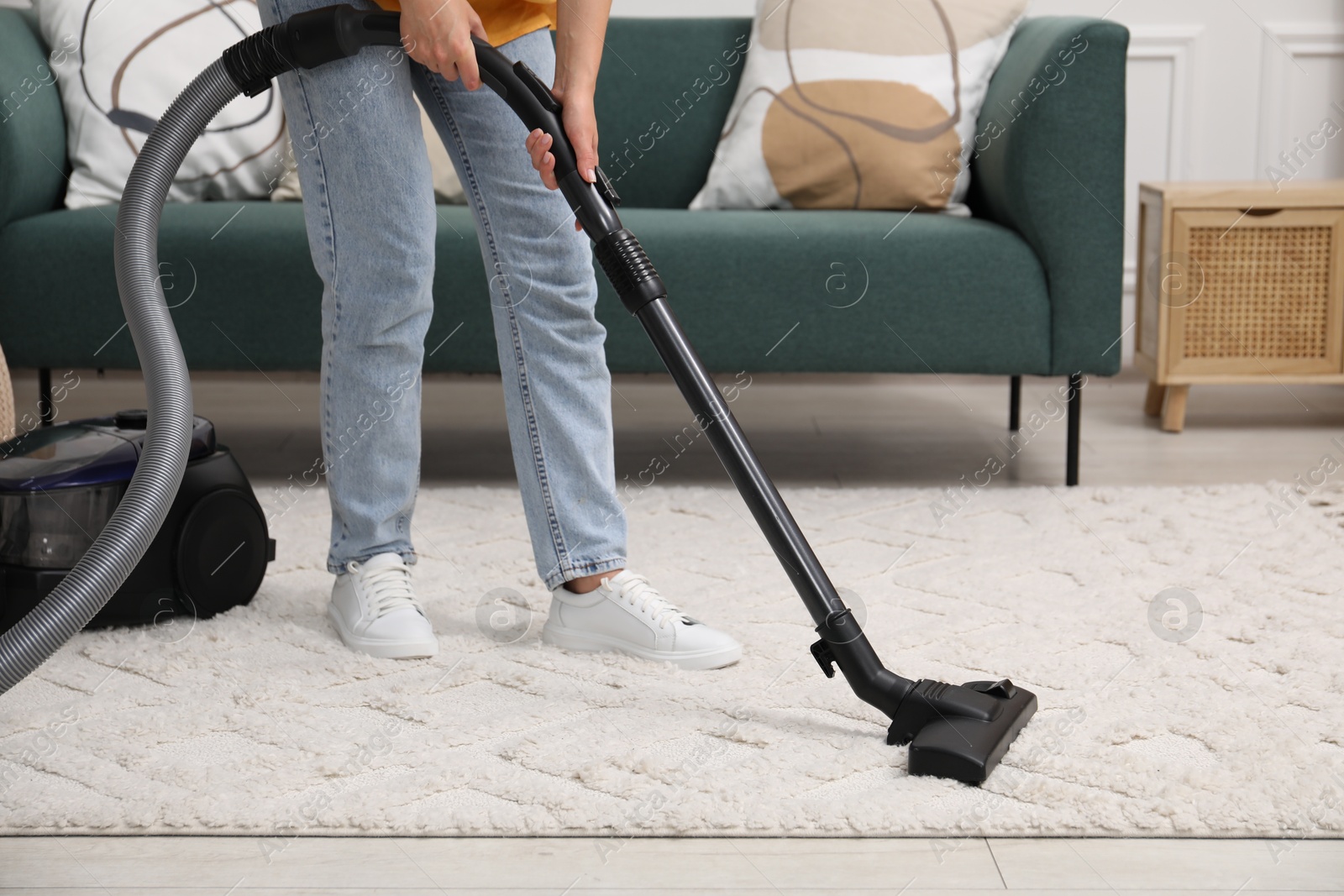 Photo of Woman cleaning carpet with vacuum in living room, closeup