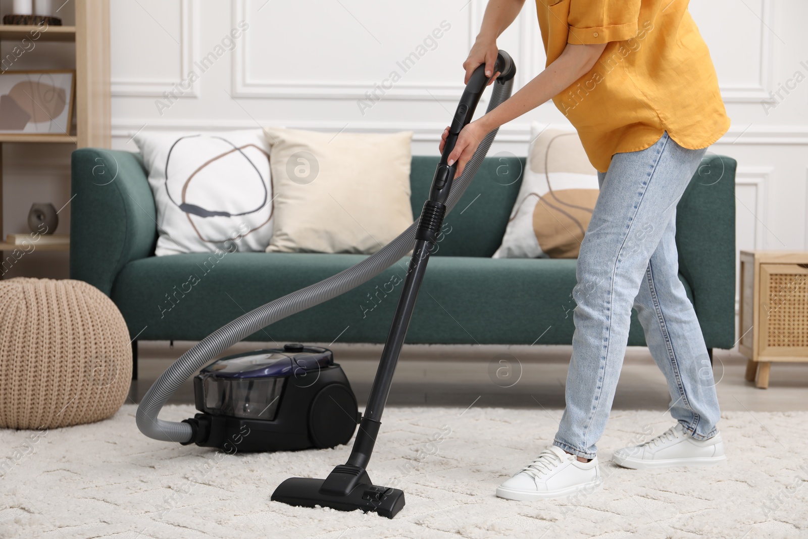 Photo of Woman cleaning carpet with vacuum in living room, closeup