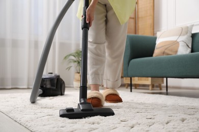 Photo of Woman cleaning carpet with vacuum in living room, closeup