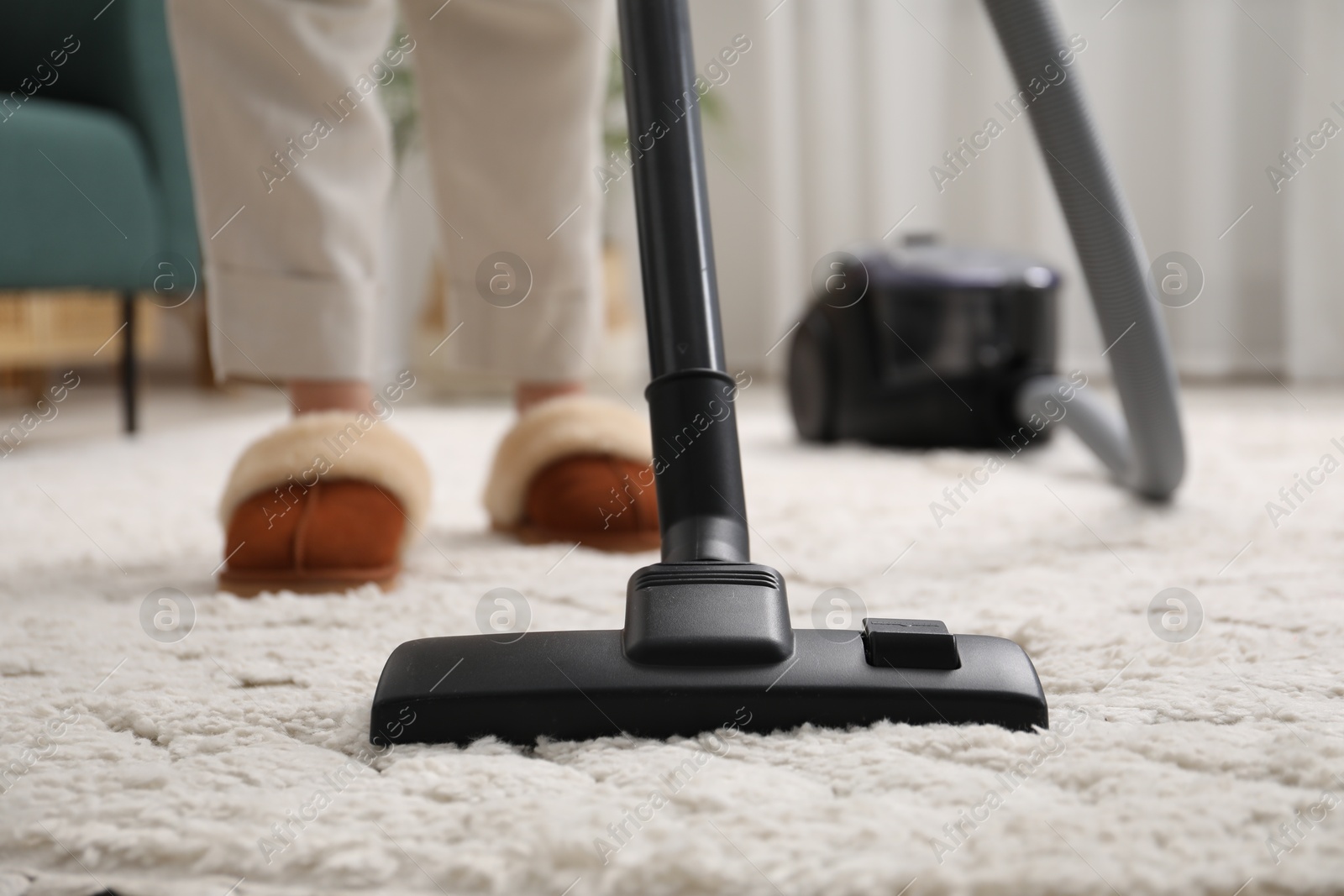 Photo of Woman cleaning carpet with vacuum indoors, closeup