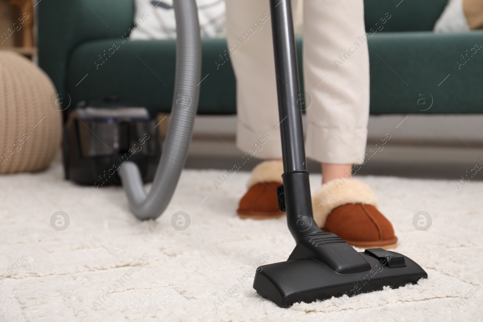 Photo of Woman cleaning carpet with vacuum indoors, closeup