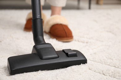 Woman cleaning carpet with vacuum indoors, closeup