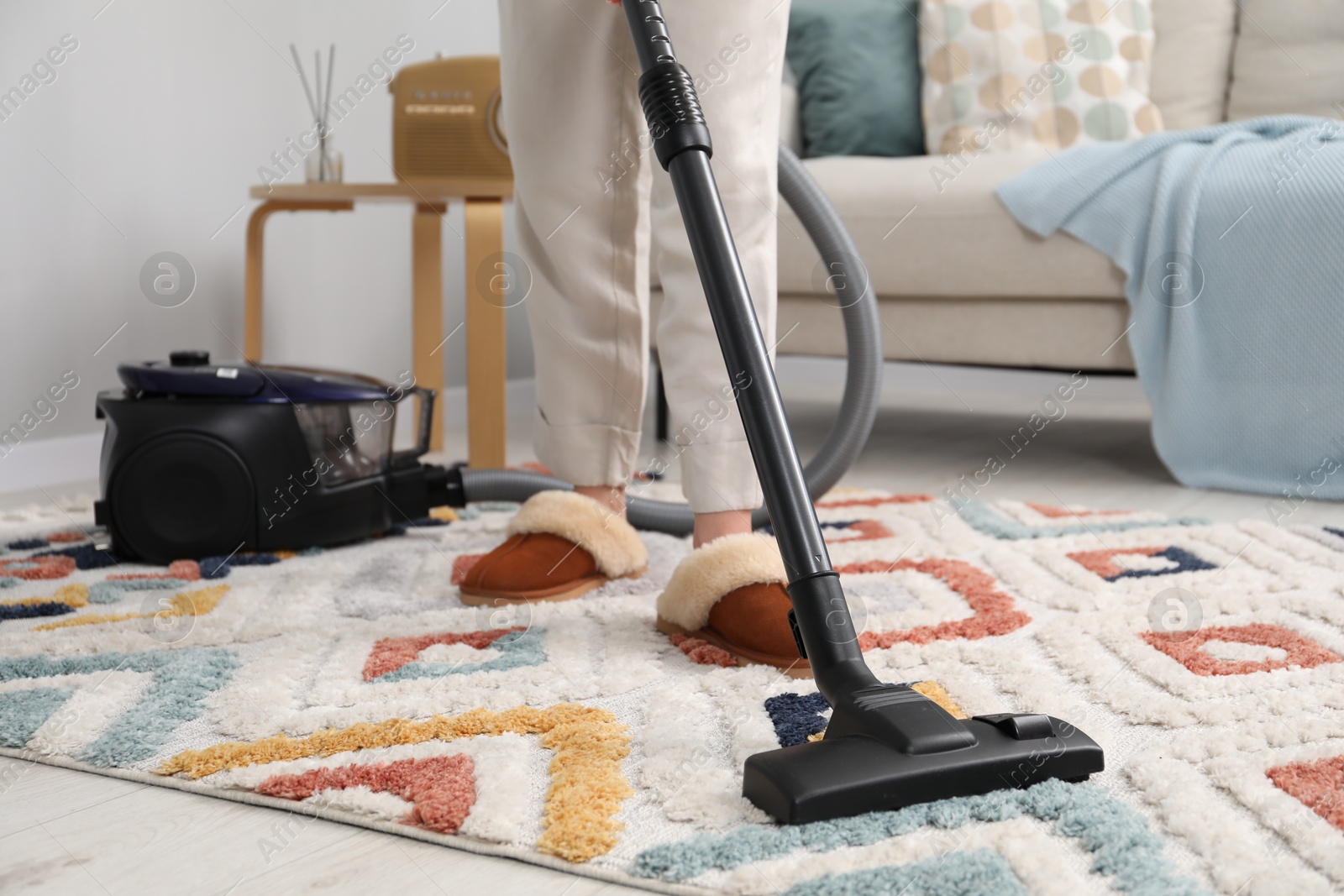 Photo of Woman cleaning carpet with vacuum indoors, closeup