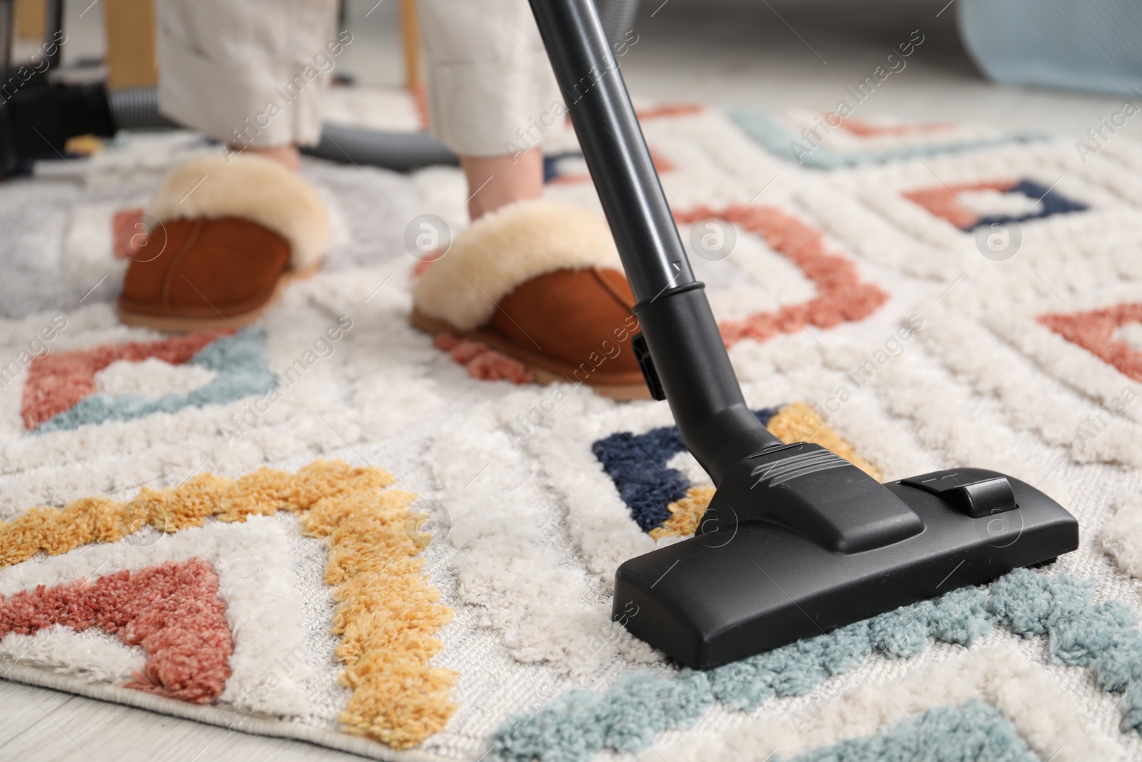 Photo of Woman cleaning carpet with vacuum indoors, closeup