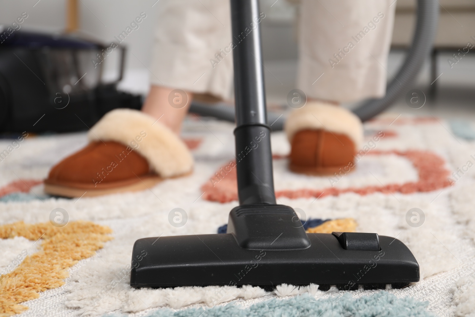 Photo of Woman cleaning carpet with vacuum indoors, closeup