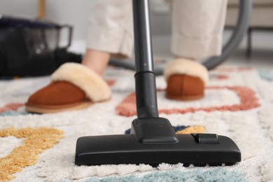 Photo of Woman cleaning carpet with vacuum indoors, closeup