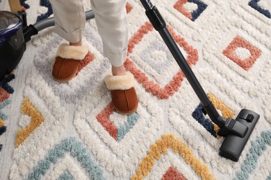 Photo of Woman cleaning carpet with vacuum, top view