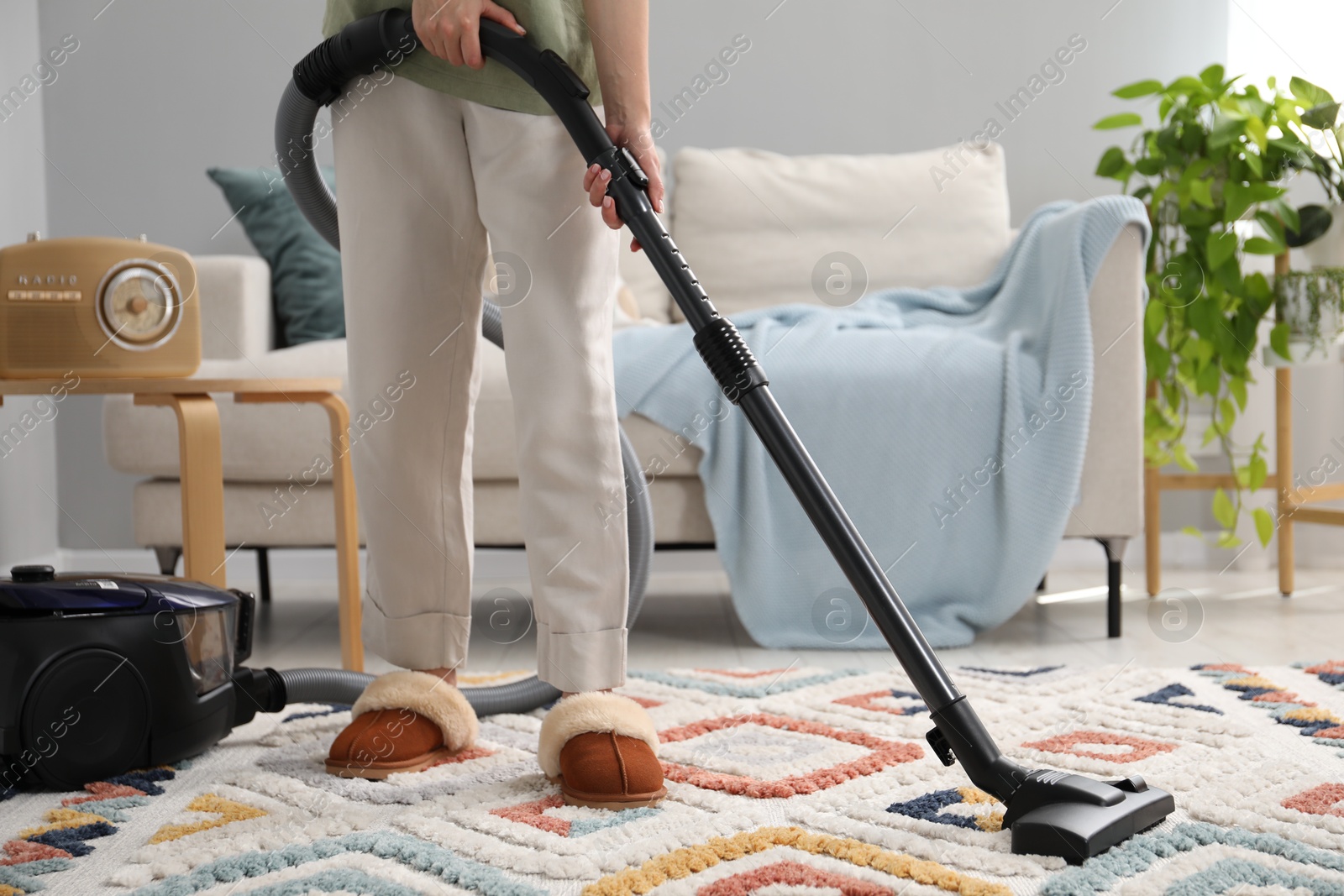 Photo of Woman cleaning carpet with vacuum in living room, closeup