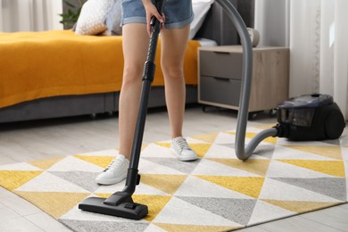 Woman vacuuming carpet at home, closeup view