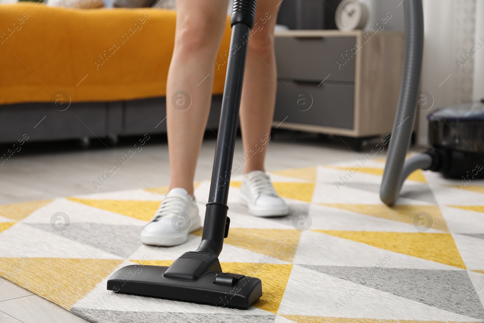 Photo of Woman vacuuming carpet at home, closeup view