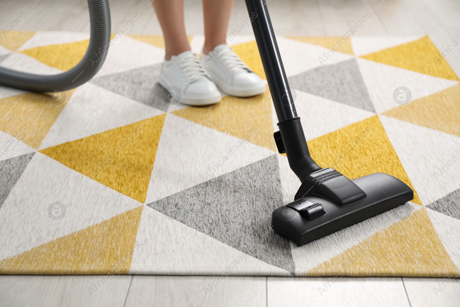 Photo of Woman vacuuming carpet at home, closeup view