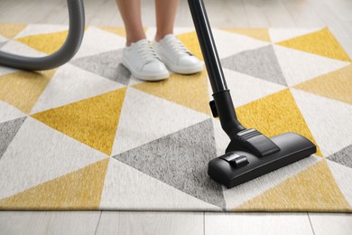 Photo of Woman vacuuming carpet at home, closeup view