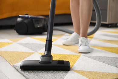 Woman vacuuming carpet at home, closeup view