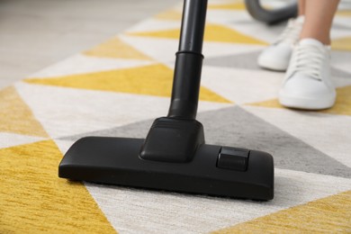 Woman vacuuming carpet at home, closeup view