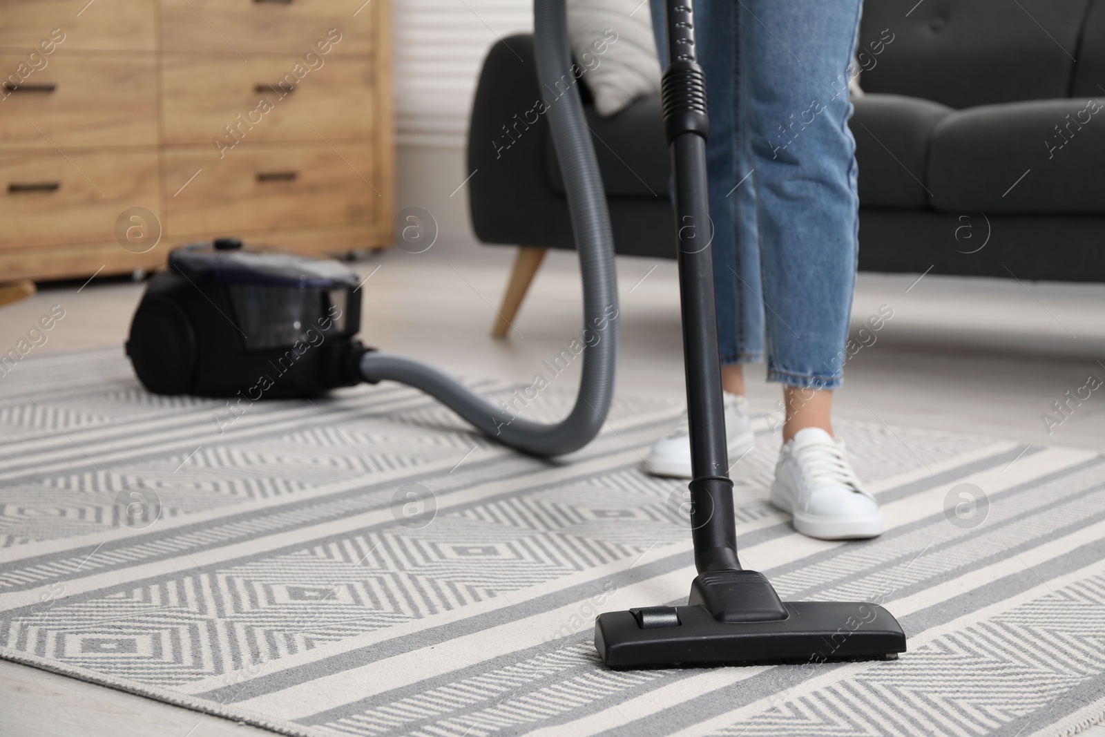 Photo of Woman vacuuming carpet at home, closeup view