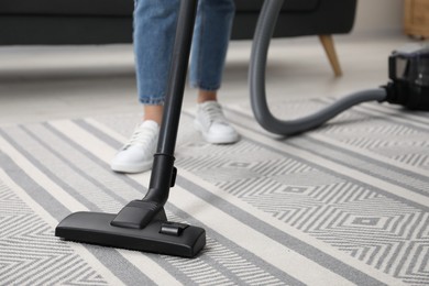 Photo of Woman vacuuming carpet at home, closeup view