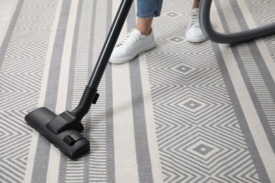 Photo of Woman vacuuming carpet at home, closeup view