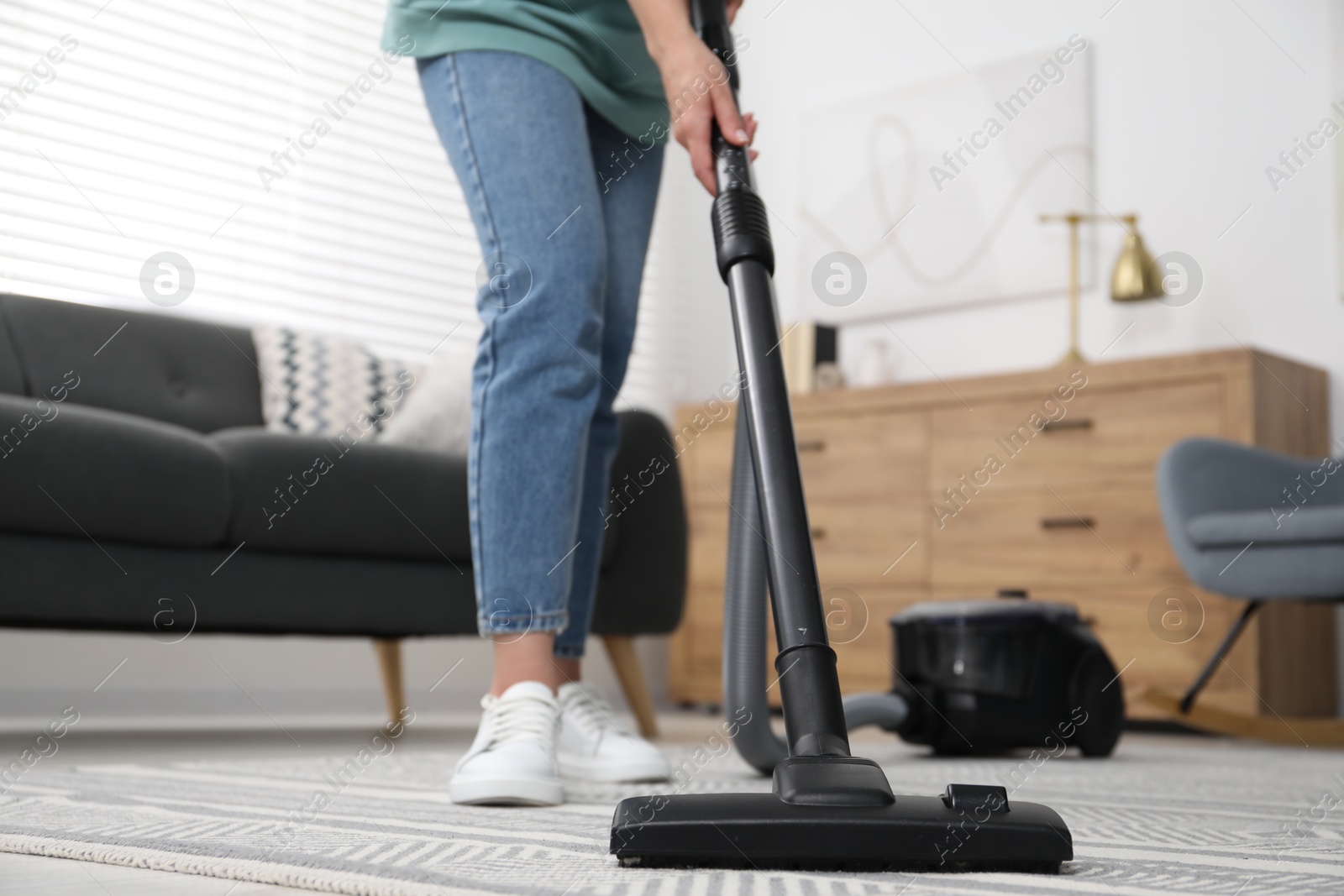 Photo of Woman vacuuming carpet at home, closeup view