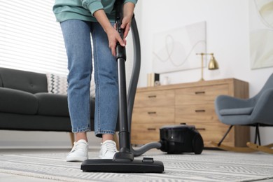 Photo of Woman vacuuming carpet at home, closeup view